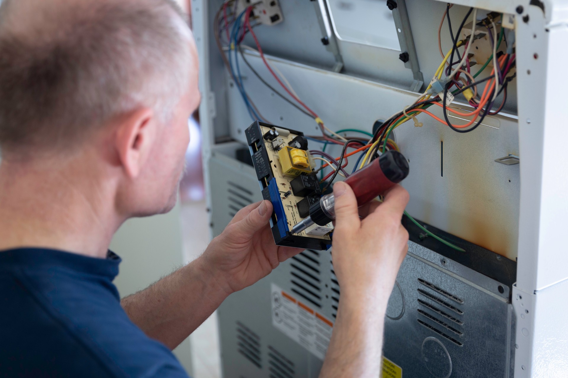 man fixing the wires in the back of electric stove